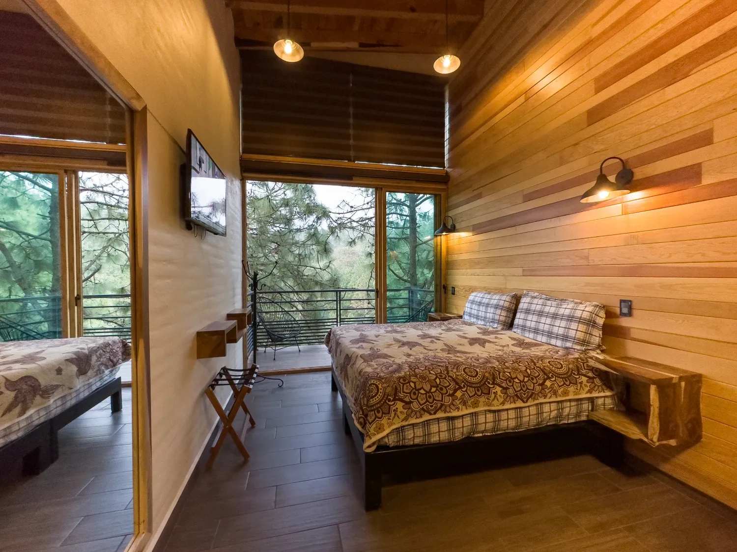 Recámara con grandes ventanales, cama King y vista al bosque en la cabaña