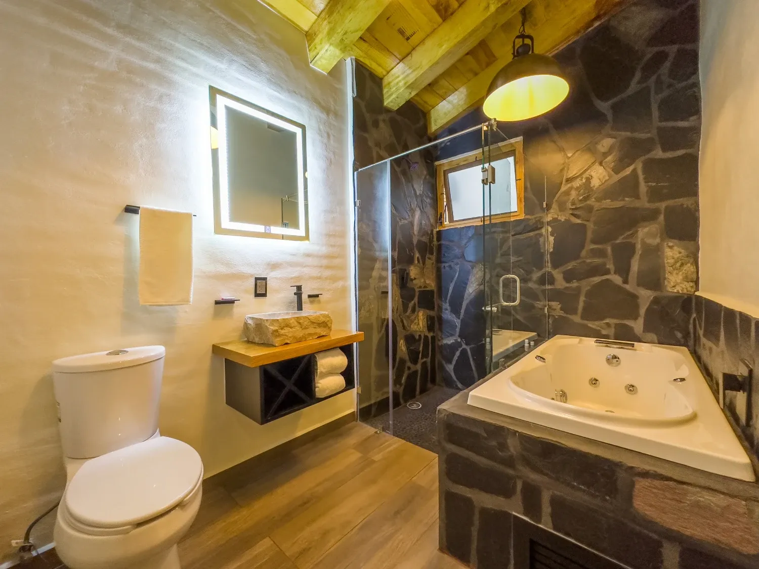 Baño con jacuzzi y muro de piedra volcánica en la cabaña de Mazamitla