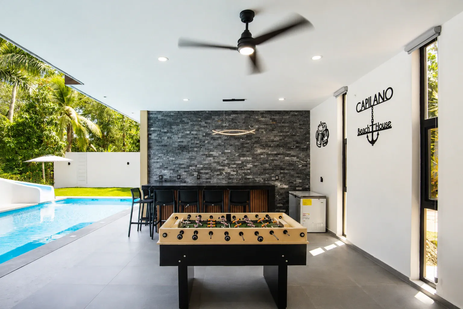 Terraza con comedor al aire libre, alberca, barra y futbolito bajo la palapa